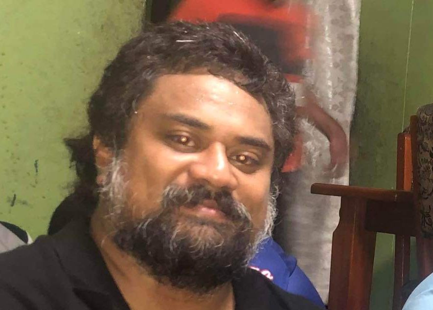 Three men sitting in a room smiling at the camera.